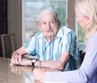 Patient on oxygen talks with his provider.